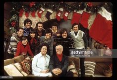 a group of people posing for a photo in front of stockings and stockings on the fireplace