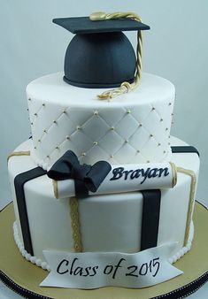 a graduation cake is decorated with white frosting and black ribbon, topped with a graduate's cap