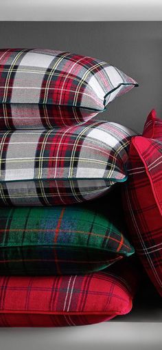 four pillows stacked on top of each other in different colors and patterns, with the same plaid pattern