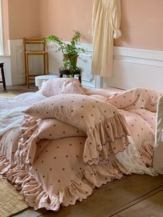 an unmade bed with pink sheets and polka dots on it in front of a window