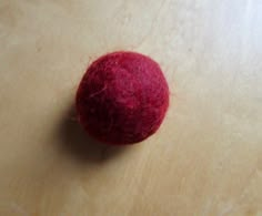 a red ball sitting on top of a wooden table next to a piece of cloth