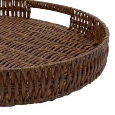 a brown wicker basket with handles on a white background for use as a serving tray