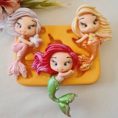 three little mermaid figurines sitting on top of a yellow tray