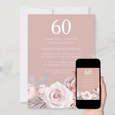 a person holding an iphone next to a pink and white floral 60th birthday party card