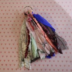 an assortment of scarves hanging from a hook on a wall with hearts in the background