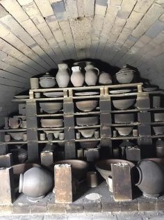 many pots and vases are stacked up in a brick oven