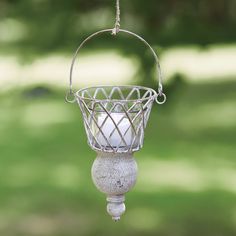 a bird feeder hanging from a wire with a candle in it's basket on the outside