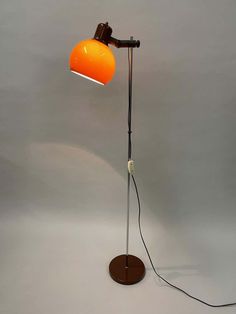 an orange lamp on a white background with a black cord attached to the light fixture