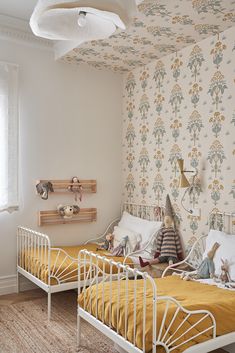 two twin beds in a bedroom with floral wallpaper