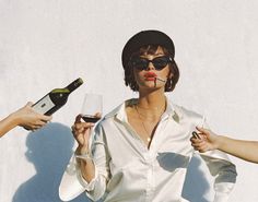 two women are holding wine glasses and one woman is wearing sunglasses with lipstick on her lips