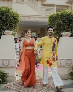 a man and woman are standing on a rug in front of a building