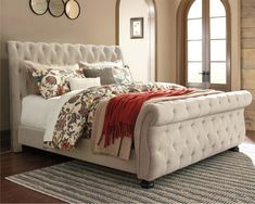 a white bed sitting on top of a wooden floor next to a rug and window