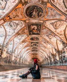 a woman sitting on the floor in an ornate building with painted ceilings and ceilinging