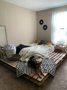 a bed made out of pallets with a dog on the floor next to it