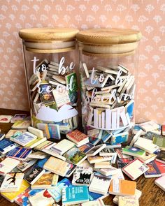 two glass jars filled with books on top of a table