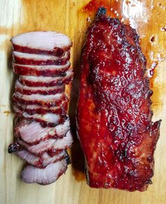 sliced meat sitting on top of a wooden cutting board next to another piece of meat