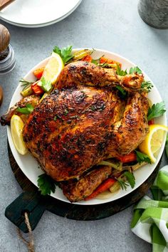 a whole chicken on a plate with lemons and parsley garnishes