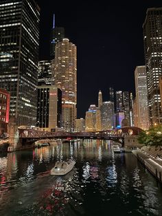 the city is lit up at night with boats in the water