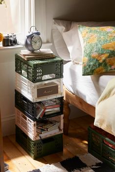 a stack of boxes sitting on top of a wooden floor in front of a bed