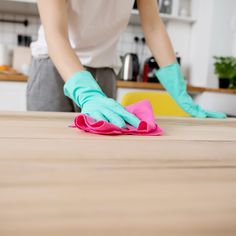 a person in blue gloves wiping up a table with a pink cloth on top of it