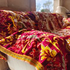 a red and yellow blanket sitting on top of a couch