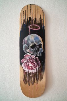 a skateboard with a skull on it and flowers painted on the bottom half of it