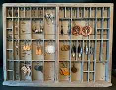 an old wooden display with earrings and earring hooks hanging on the wall next to it