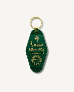 a green keychain with the name and logo on it, in gold lettering