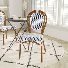 three chairs and a table in a room with white walls, windows and rugs