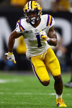 a football player running with the ball in his hand while wearing yellow and white uniform