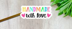 a sticker that says handmade with love on it next to some green leaves