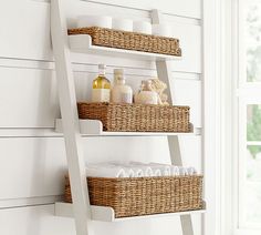 a bathroom shelf with three baskets and soaps on it next to a white wall