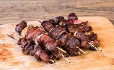 several skewered meats are sitting on a cutting board