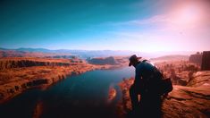 a man standing on top of a cliff next to a lake in the middle of nowhere