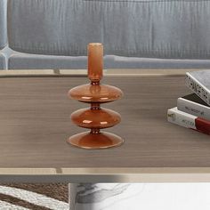 a glass candle holder sitting on top of a coffee table next to two bookends