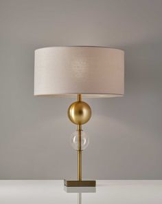 a lamp that is on top of a white table with a beige shade over it