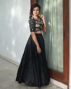 a woman standing in front of a window wearing a black skirt and cropped top