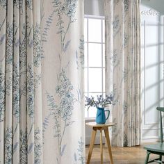 a blue vase sitting on top of a table next to a window covered in curtains