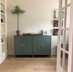 a green cabinet sitting in the corner of a room with a potted plant on top