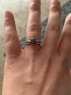 a woman's hand with a diamond ring on top of her finger and the other half of her thumb