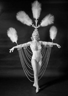 a black and white photo of a woman with feathers on her head