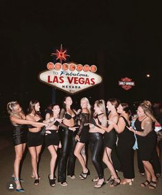 a group of women standing next to each other in front of a las vegas sign