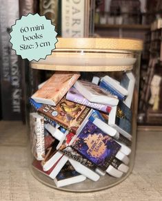 a glass jar filled with books on top of a table