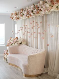 a white couch sitting in front of a flower covered wall with pink flowers on it