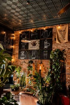 an indoor cafe with plants and lights hanging from the brick wall, along with posters on the walls