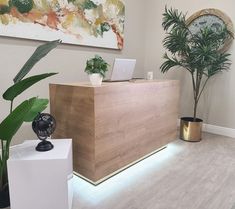 a wooden reception desk sitting next to a potted plant in front of a painting