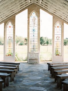 an empty church with stained glass windows and benches