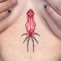 a woman's chest with a red tattoo on her stomach and two hands holding it