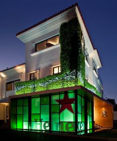 an illuminated building with a star on the side and green plants growing on it's roof