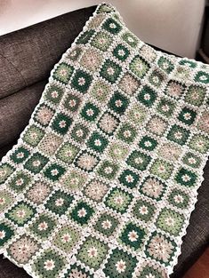 a green and white crocheted blanket sitting on top of a chair